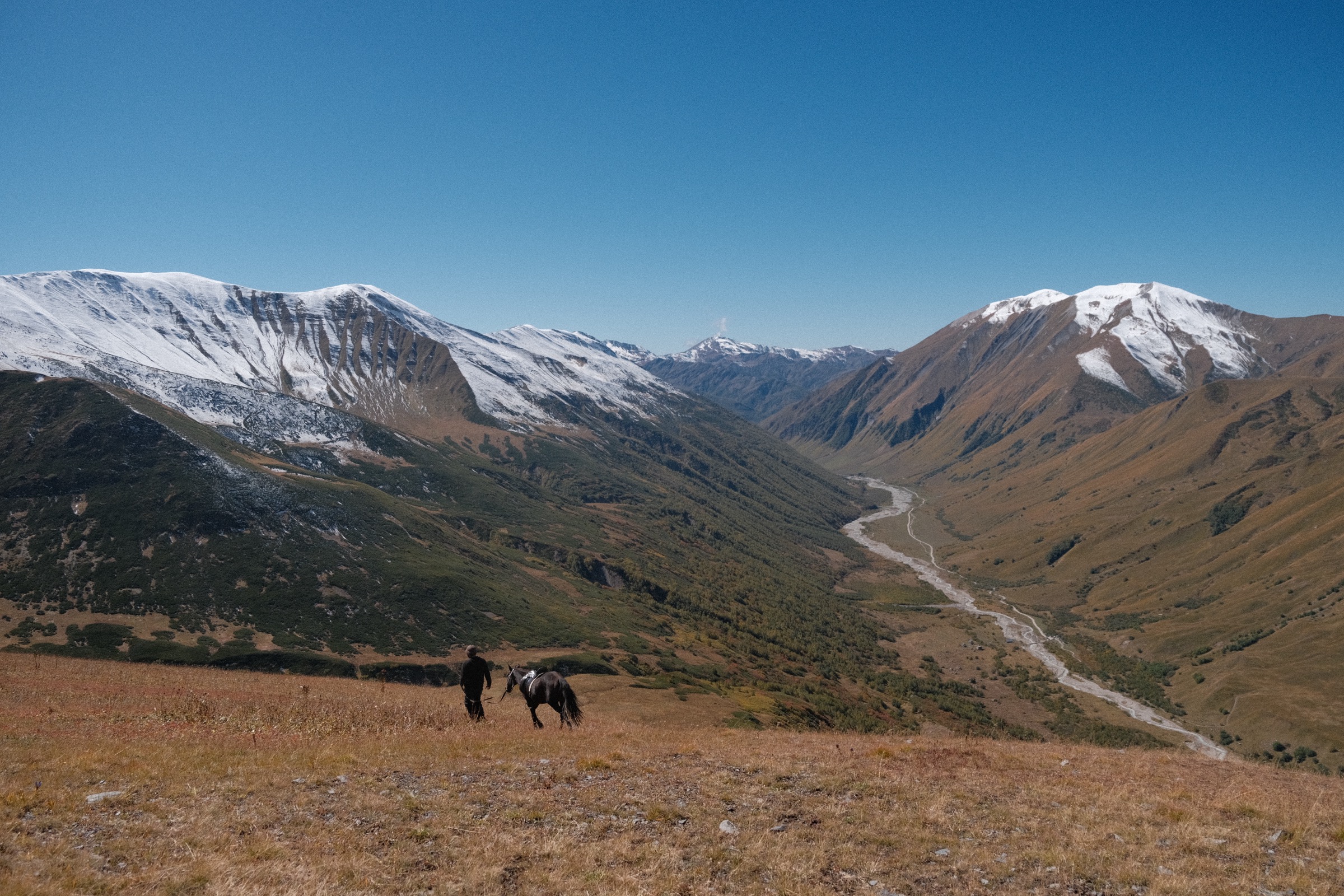 Riders descending a ridge at sunset